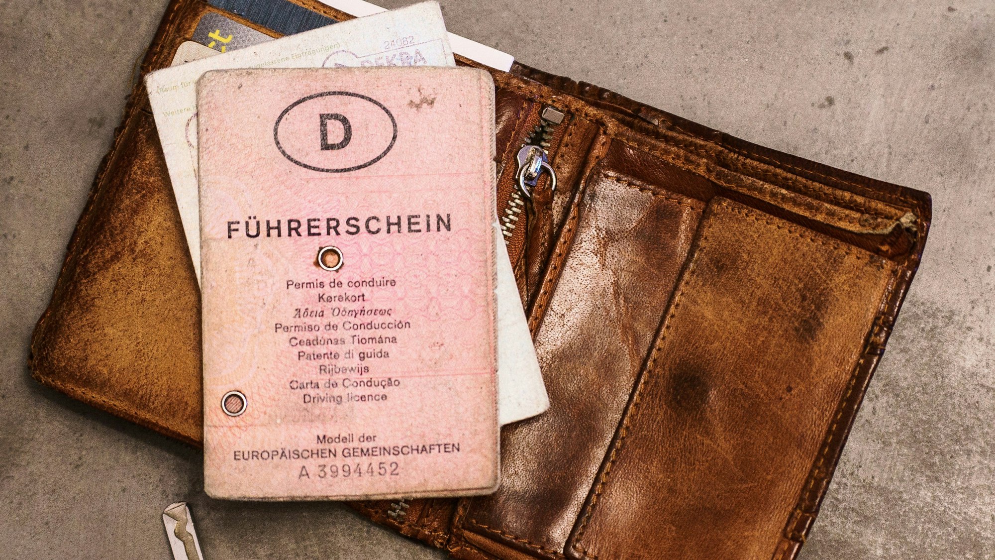 Ein «rosa Führerschein», ein Autoschlüssel, eine Geldbörse und ein Fahrzeugschein liegen auf dem Tisch.
