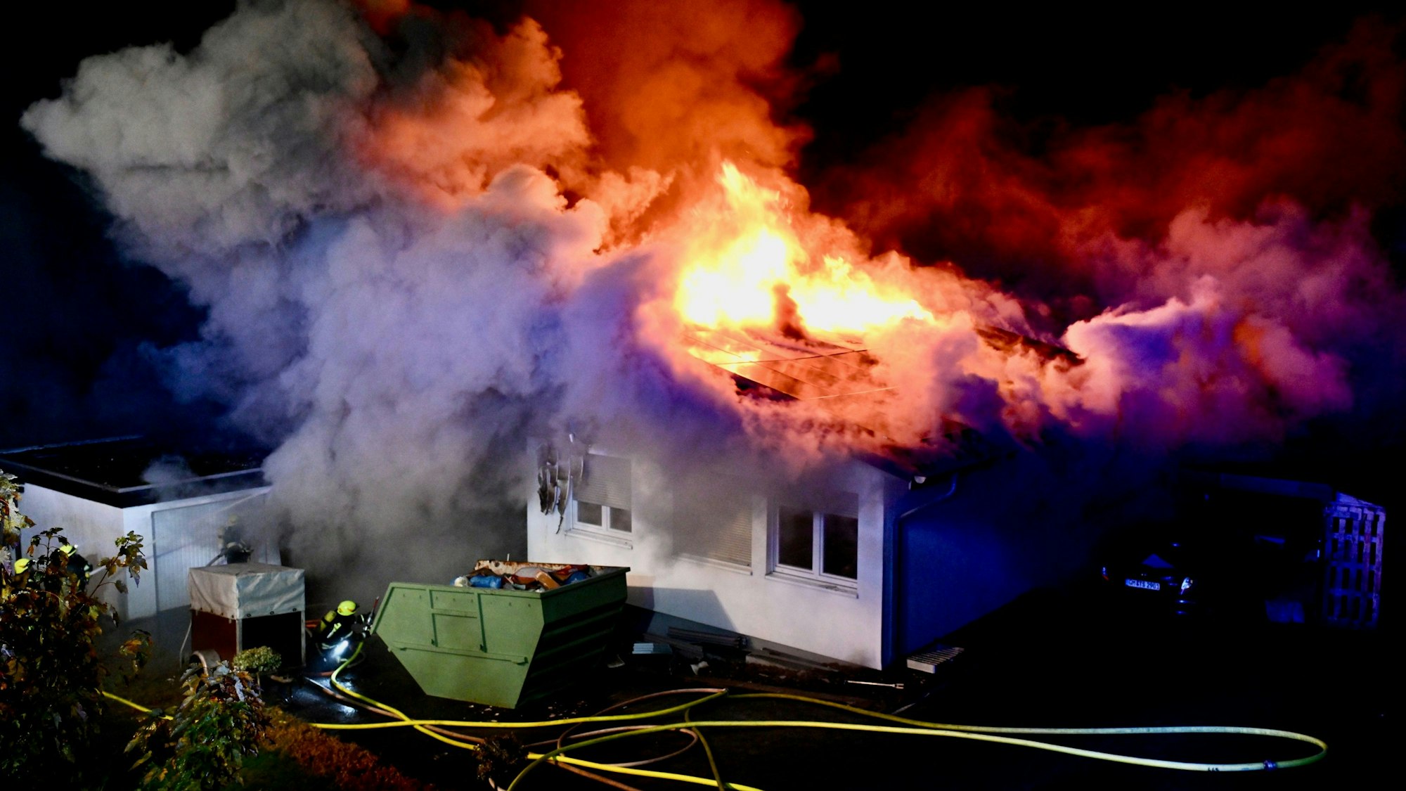 Das Dach des Einfamilienhauses steht komplett in Flammen. Die Feuerwehr bekämpft den Brand.