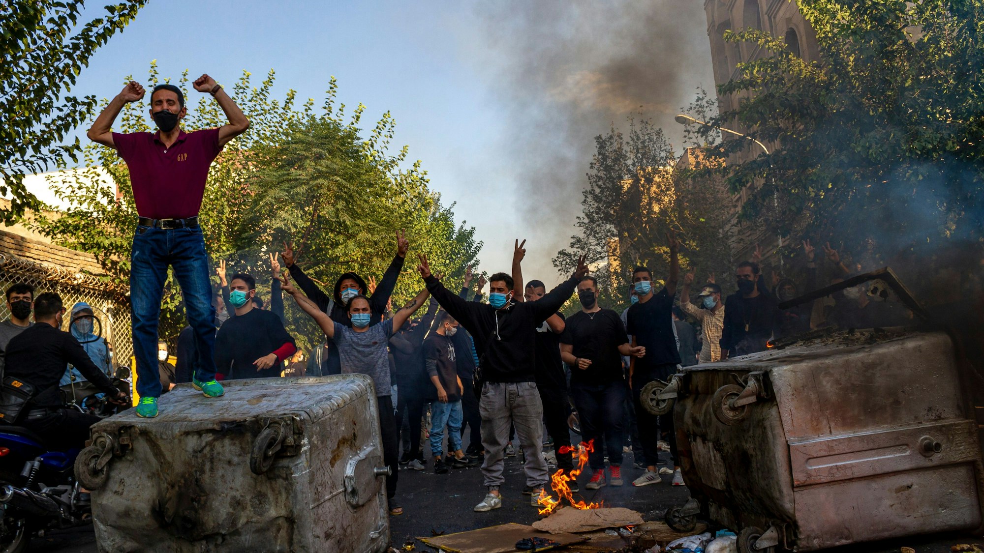 HANDOUT - 27.10.2022, Iran, Teheran:, Iraner protestieren nach dem Tod der 22-jährigen Mahsa Amini in Haft der Sittenpolizei. Zu sehen sind brennende Autos und protestierende Männer.