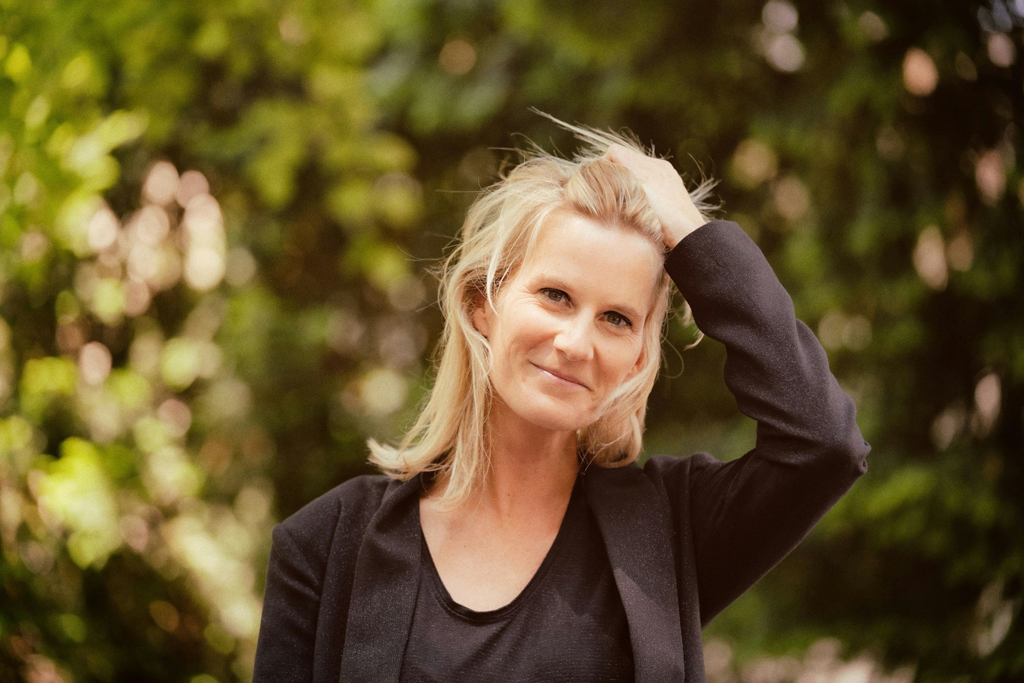 Lucy van Kuhl vor einem grünen Hintergrund, die Hand in den Haaren.