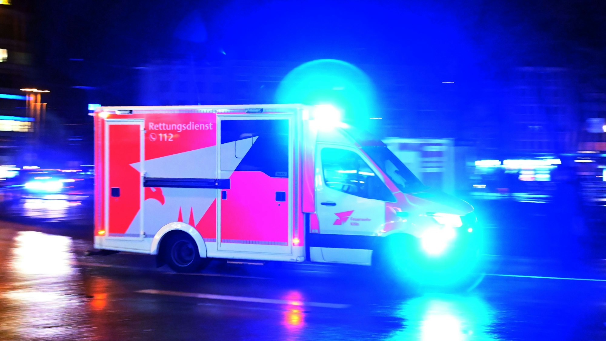 Ein Rettungswagen der Feuerwehr rast nachts über eine Straße.