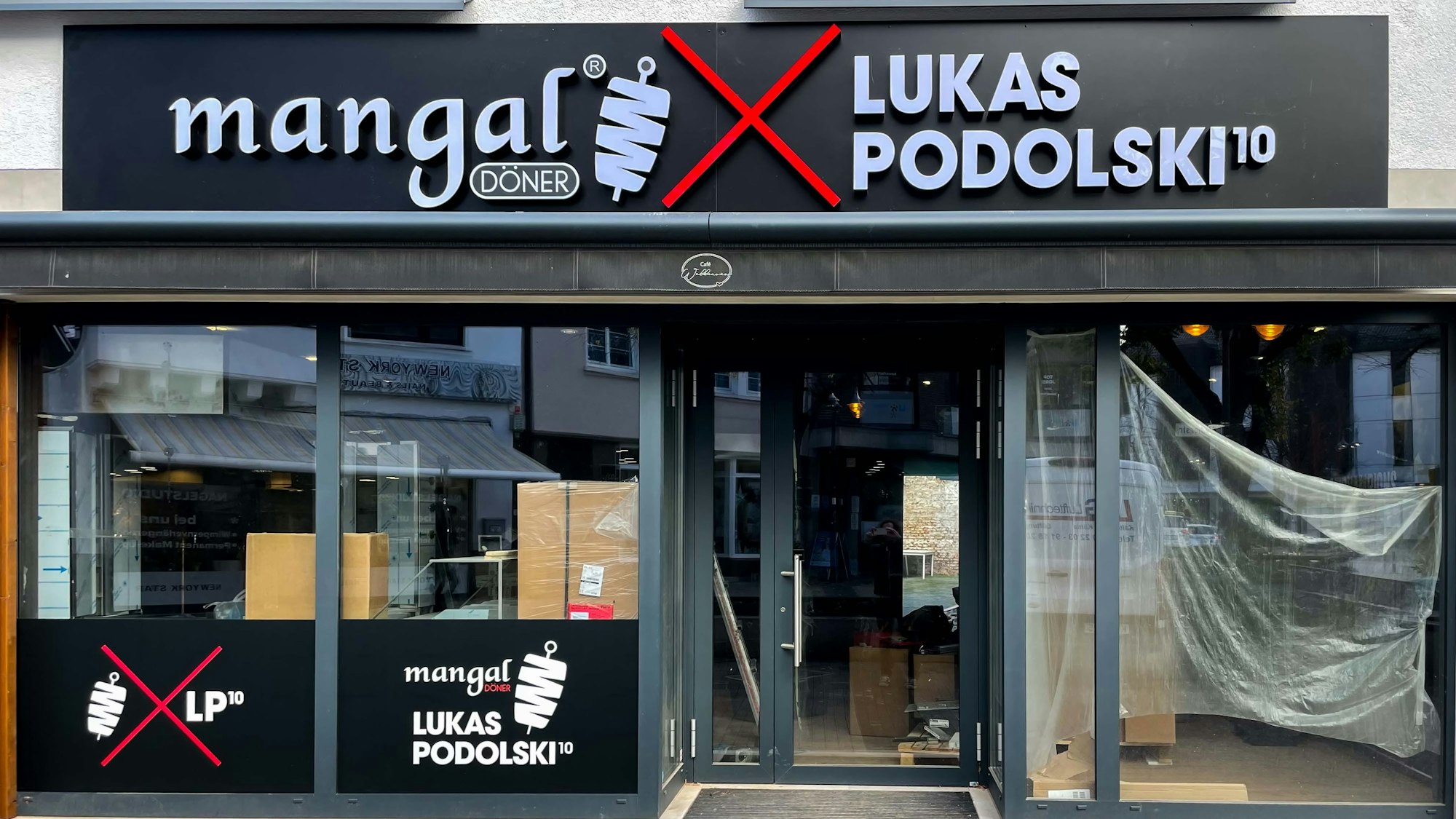 Über einem Ladenlokal ist ein Schild mit „mangal, Lukas Podolski“ angebracht, in den Innenräumen laufen noch Bauarbeiten.