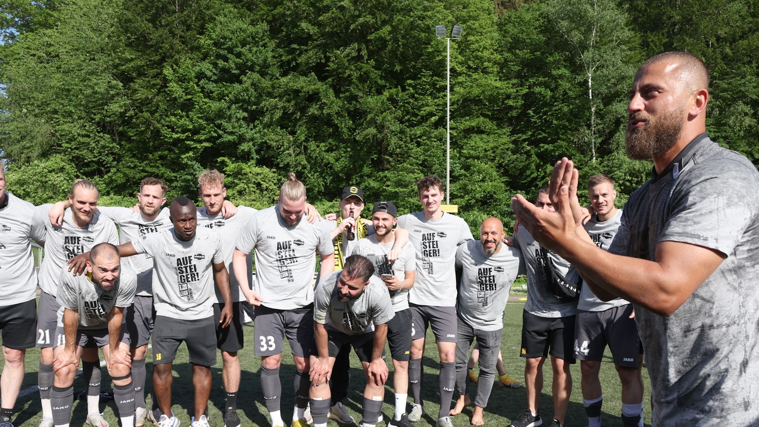 Die Mannschaft steht eng beienander, die Arme um die Schultern gelegt. Trainer Abdullah Keseroglu klatscht im Vordergrund in die Hände.
