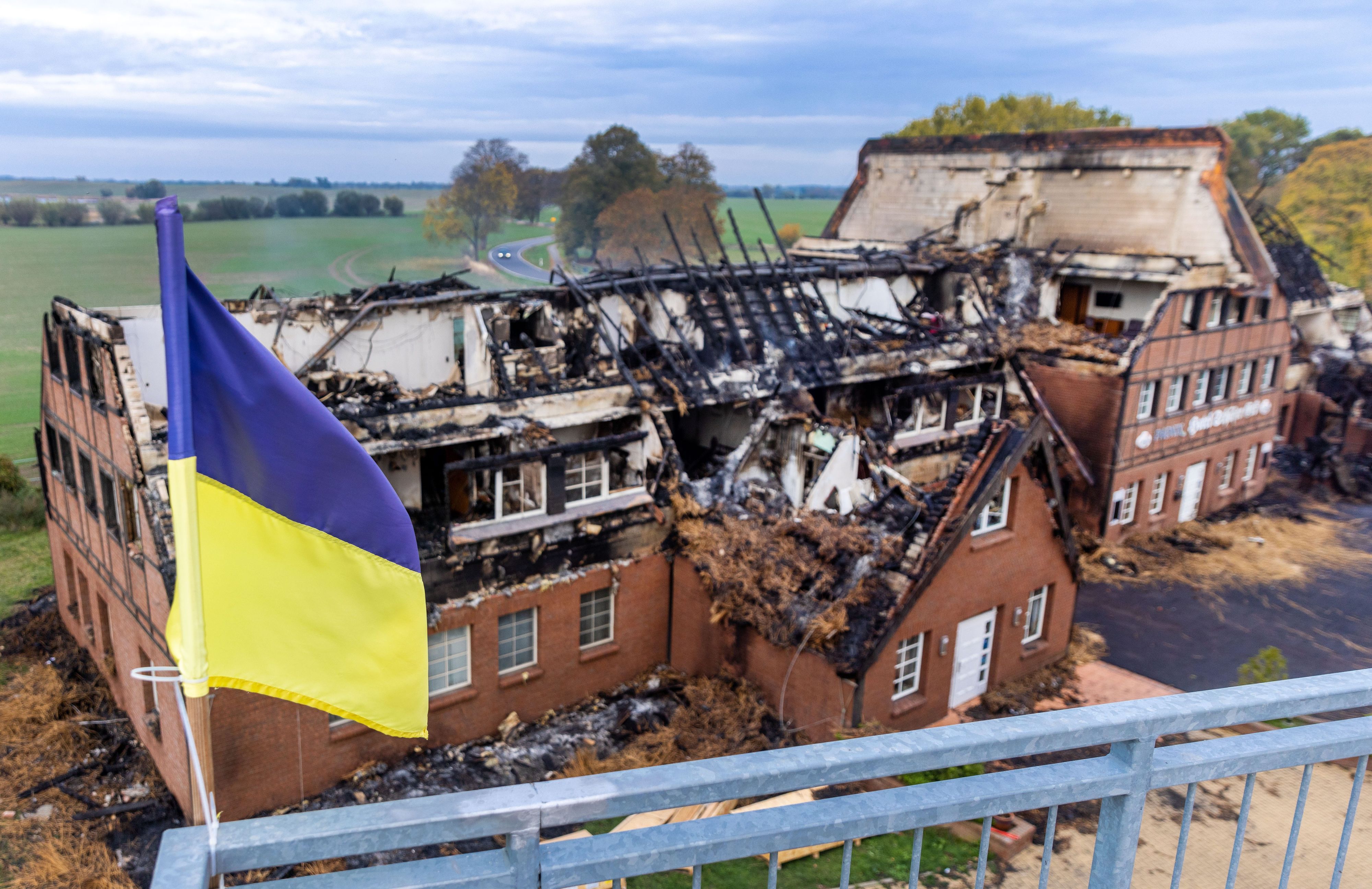 Mecklenburg-Vorpommern, Groß Strömkendorf: Die ukrainische Fahne weht auf dem Dach eines Nebengebäudes vor den Resten des abgebrannten Hotelgebäudes.