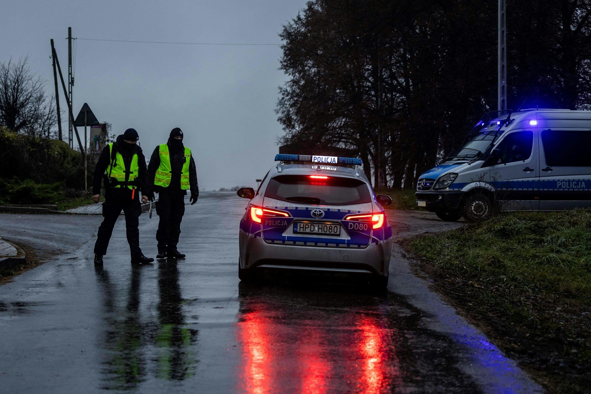 Polnische Polizisten stehen nahe dem Ort der Raketeneinschläge in Ost-Polen, sie tragen helle Warnwesten, mehrere Polizeifahrzeuge sind zu sehen.
