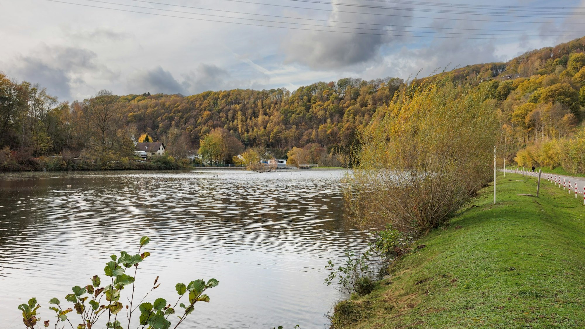 Der See liegt links im Bild, um den See stehen viele herbstliche Bäume.