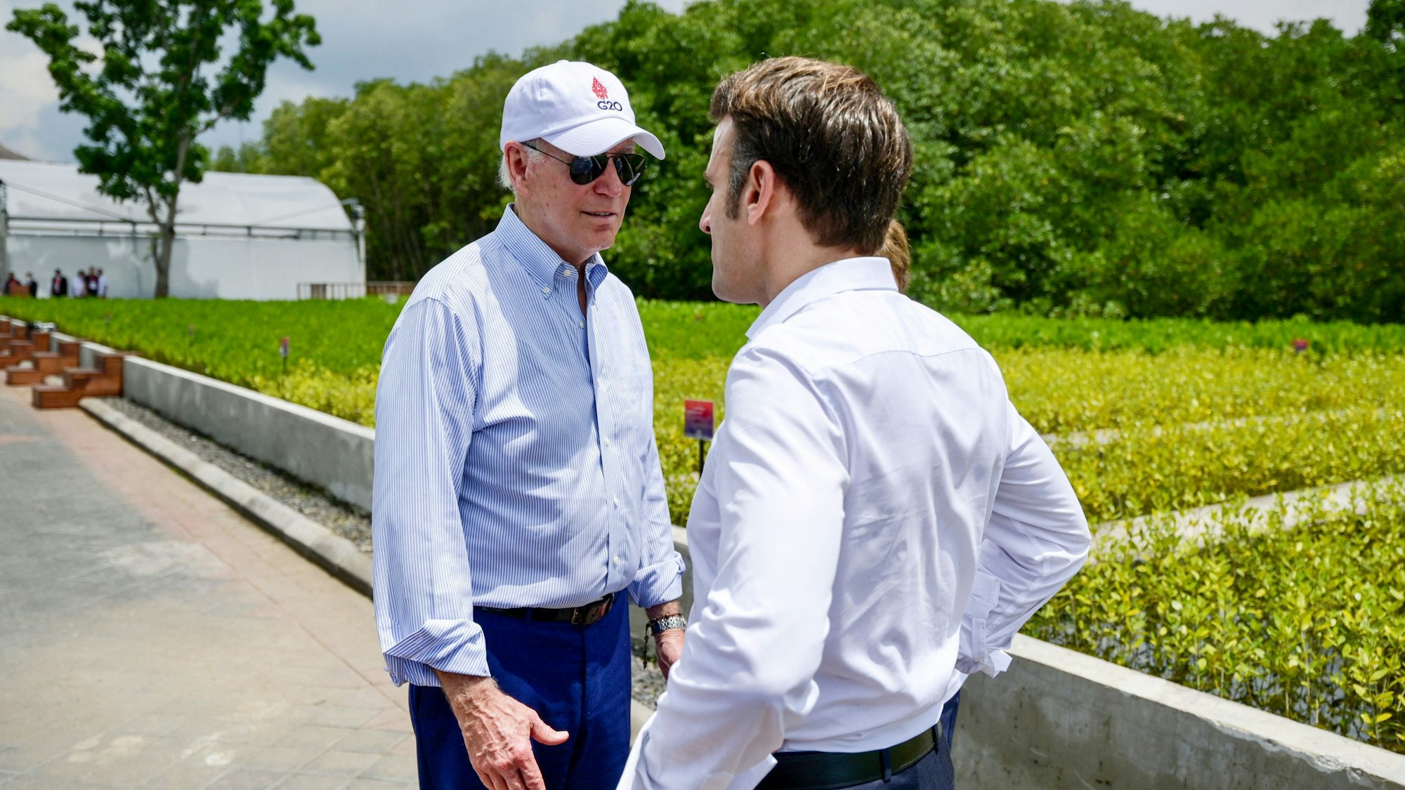 US-Präsident Joe Biden mit Baseball-Cap und Sonnenbrille im Gespräch mit dem französischen Präsidenten Emmanuel Macron (rechts) während eines Ausflugs am Rande des G20-Treffens in Indonesien.