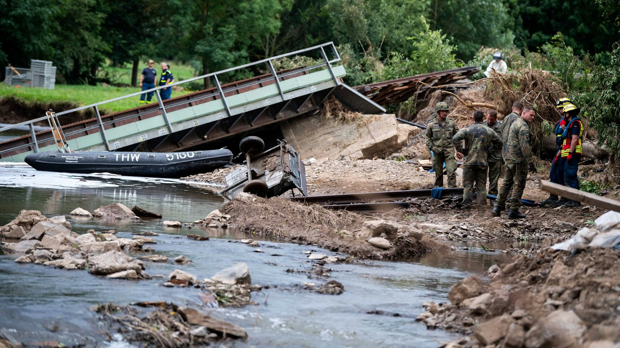 Die Brücke liegt schief in der Erft, viele Personen stehen am Ufer.