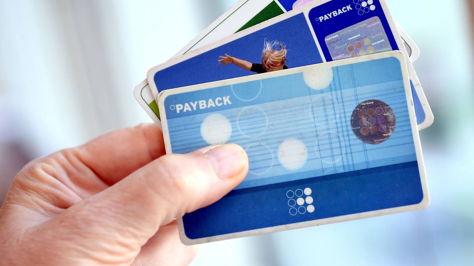 Eine Hand hält drei Payback-Karten wie einen Fächer.