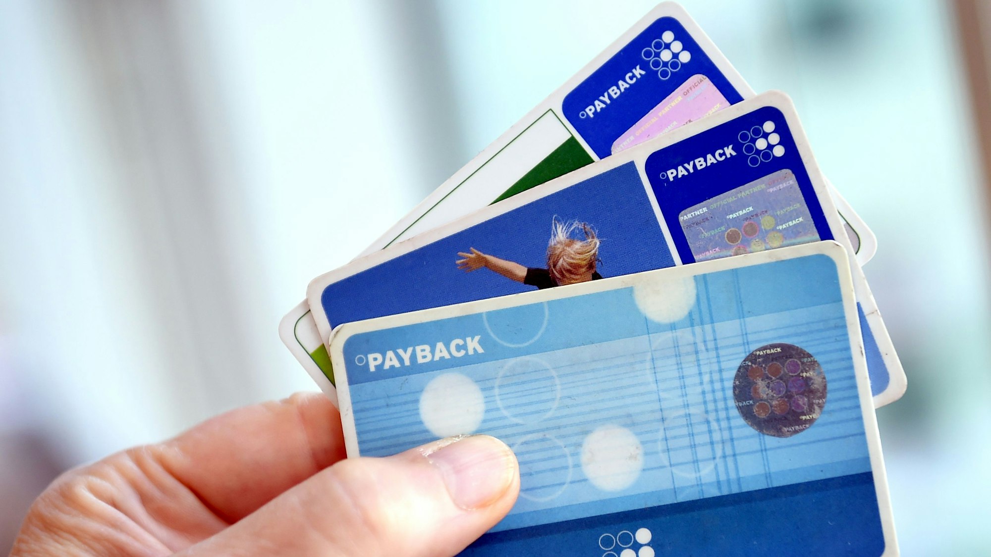 Eine Hand hält drei Payback-Karten wie einen Fächer.
