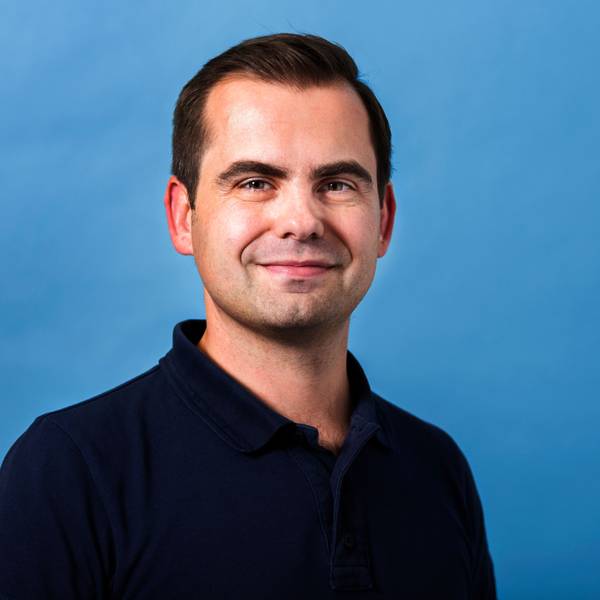 Jaroslaw Kutylowski steht vor einem blauen Hintergrund.