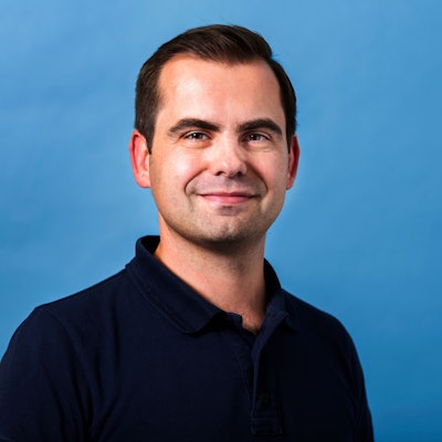 Jaroslaw Kutylowski steht vor einem blauen Hintergrund.