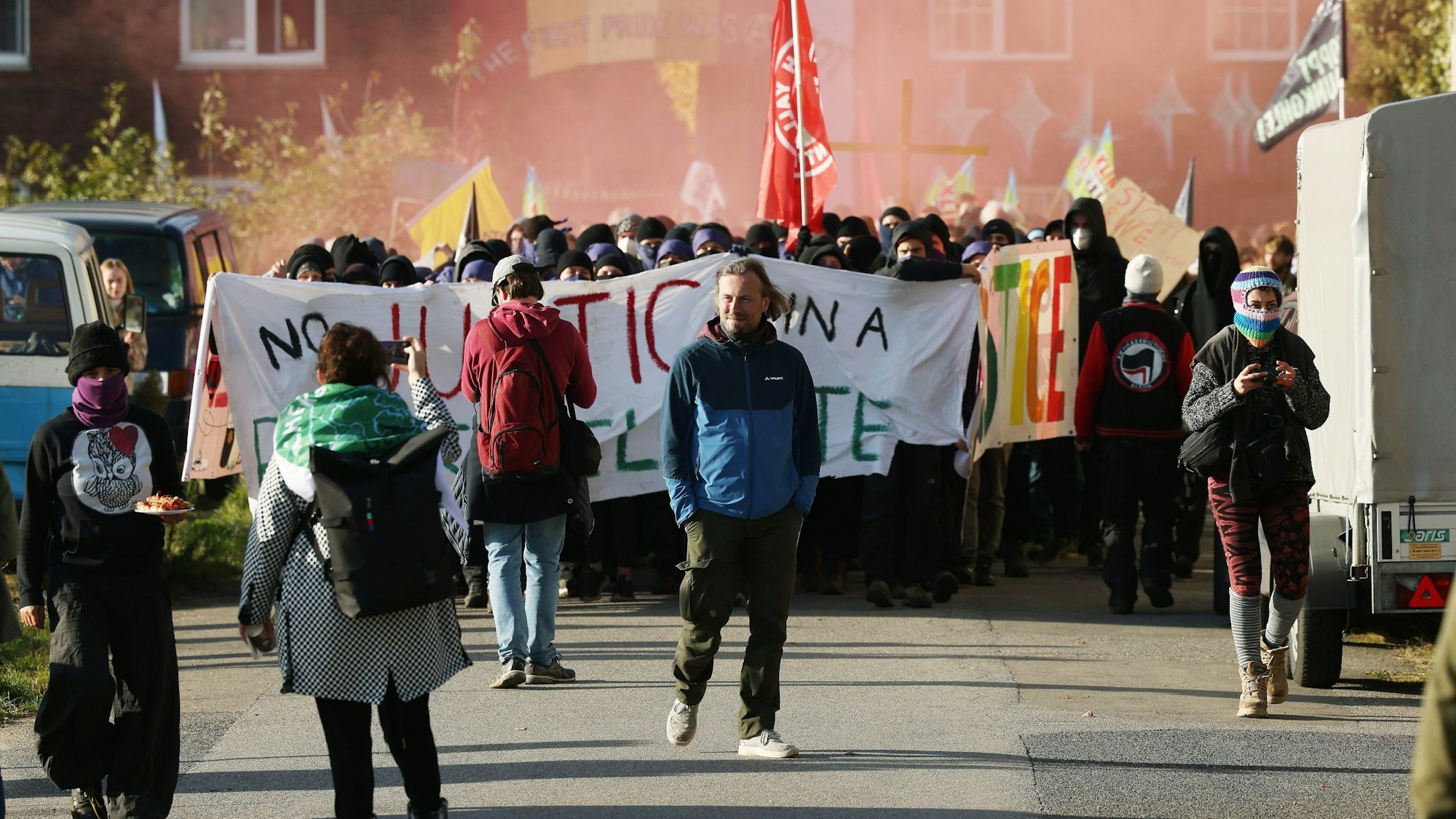 12.11.2022, Nordrhein-Westfalen, Erkelenz: Bei einer Demonstration in Lützerath ziehen Demonstranten mit einem Banner und Pyrotechnik durch das Dorf.