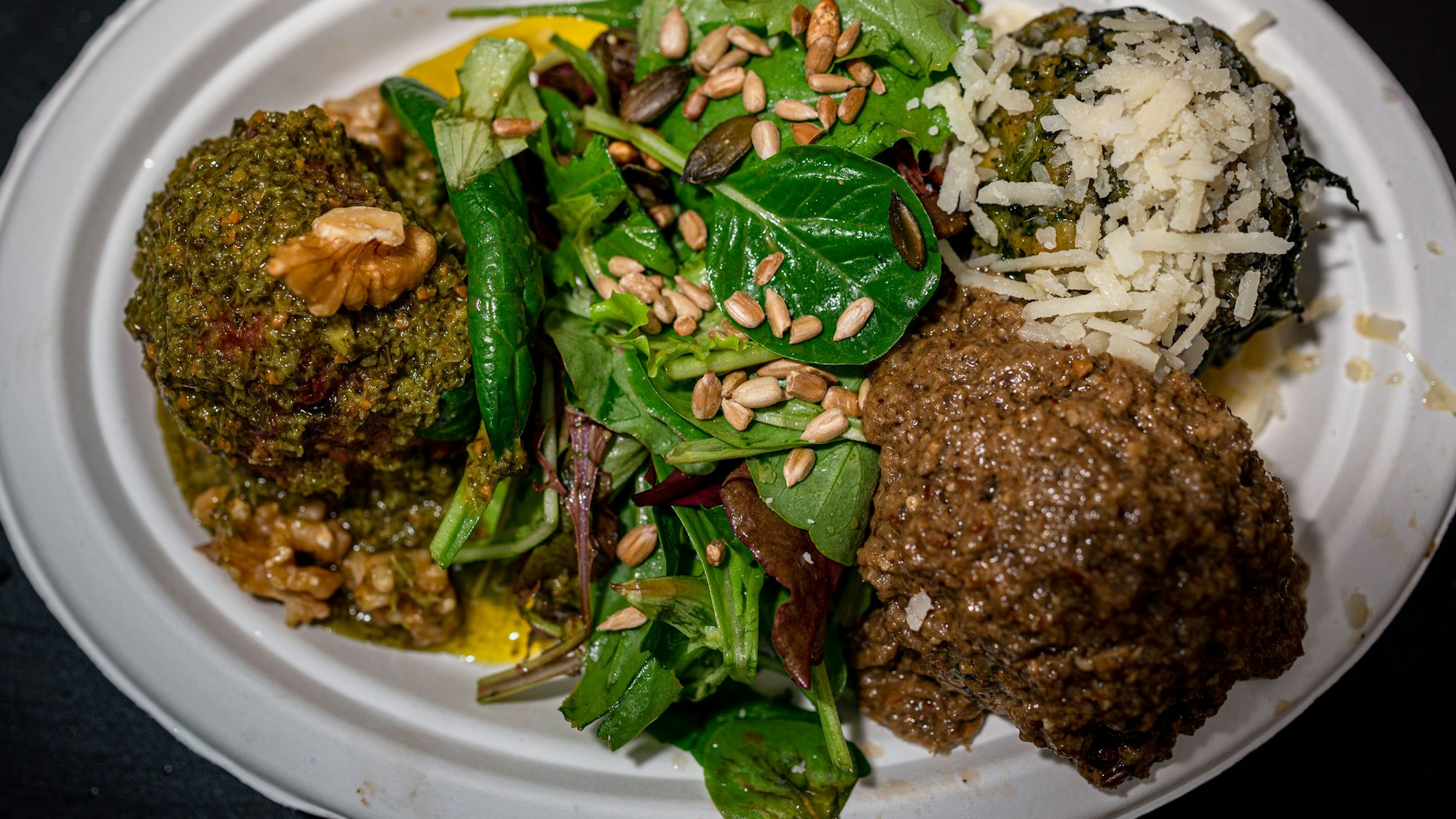 Das Bild zeigt drei Knödel von Knödelfein, die immer mit einer Salatbeilage serviert werden.