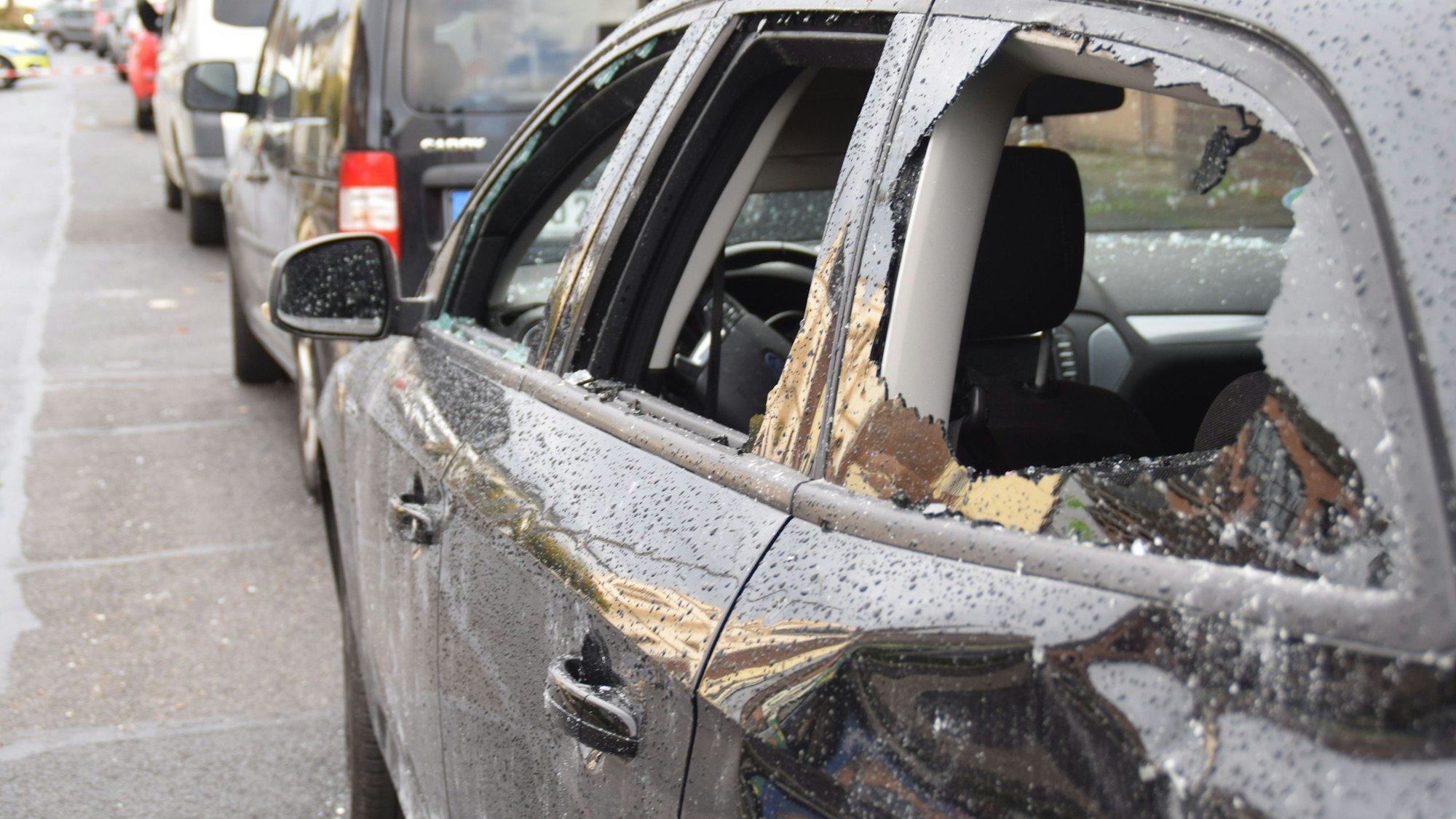 Ein gegenüber der Filiale abgestellter Pkw mit zerstörten Scheiben und Dellen.