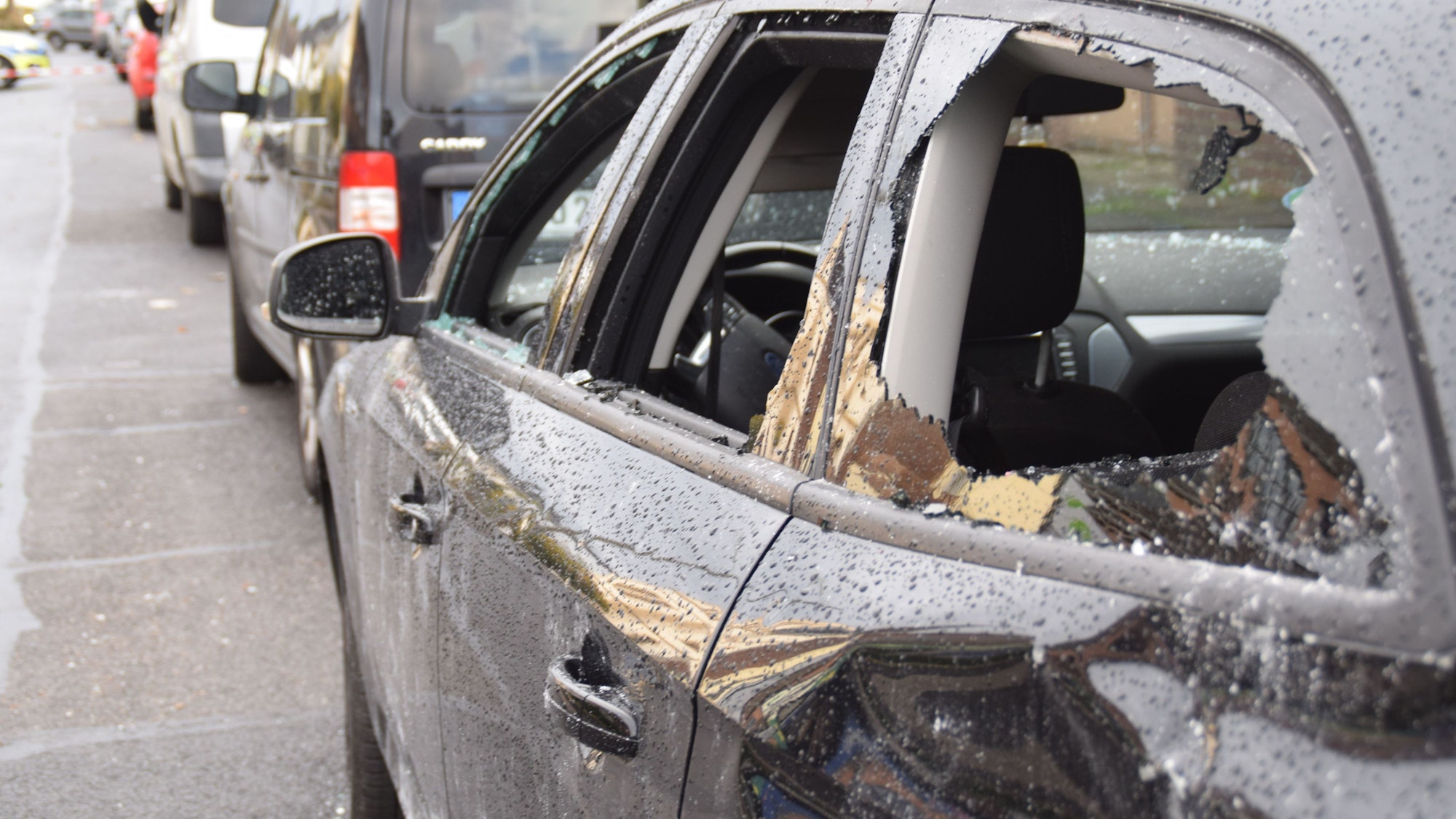 Ein gegenüber der Filiale abgestellter Pkw mit zerstörten Scheiben und Dellen.