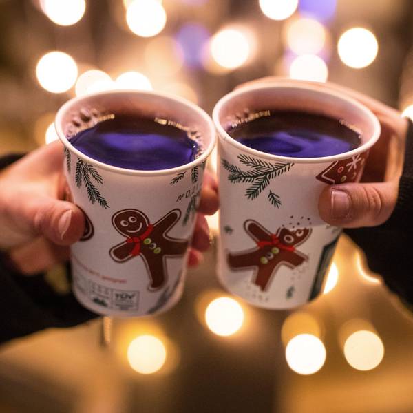 Zwei Frauen stoßen am Schlossplatz mit Glühwein gefüllten Bechern an. Symbolbild