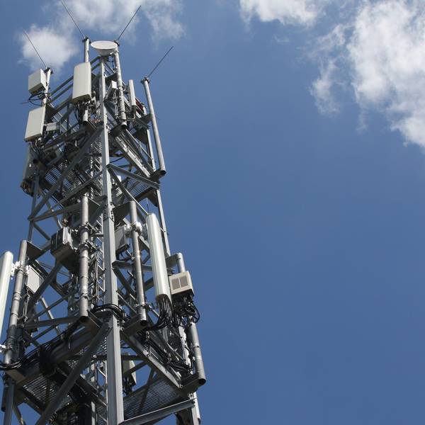 Ein Mobilfunkmast ragt in den blauen Himmmel.