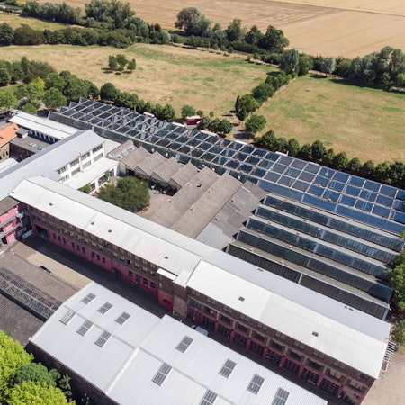 Auf dem alten Industriegelände stehen verschiedene Gebäude. Ein Großteil der Dächer ist mit Photovoltaik-Anlagen ausgestattet.