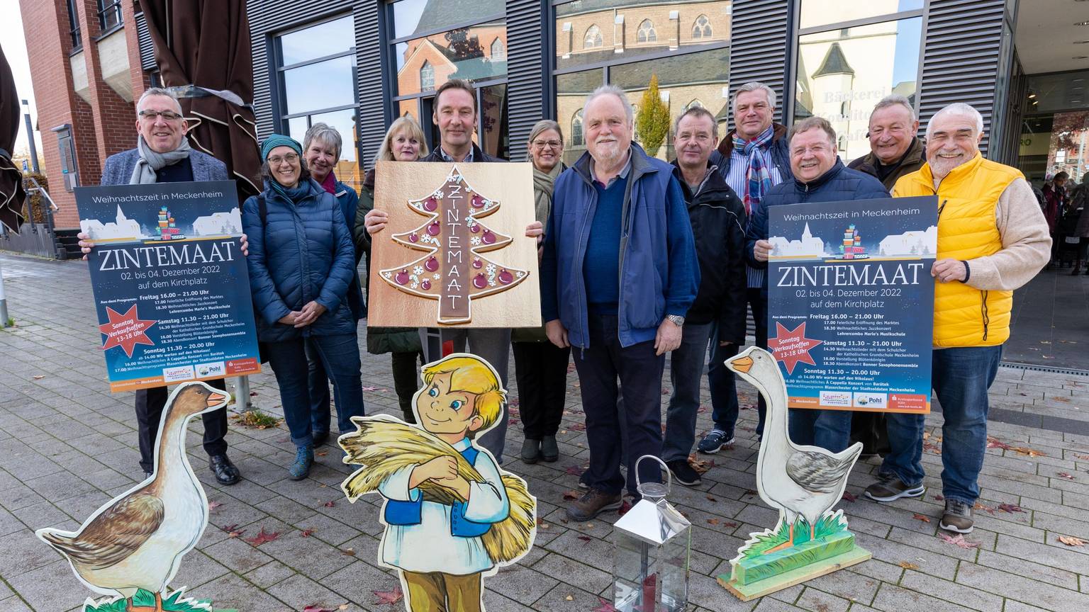 Vertreter des Verbunds, der Stadt und der Bäckerei Mauel zeigen Plakate.