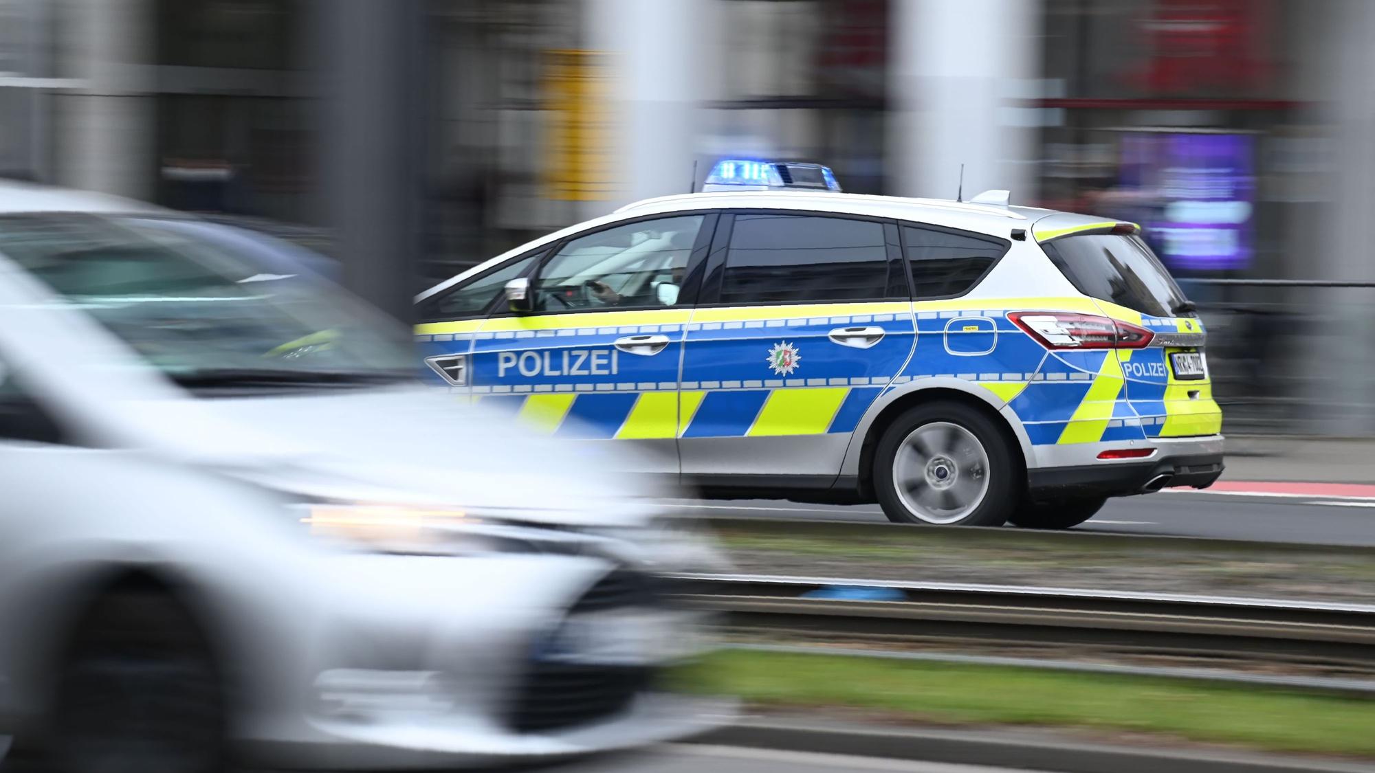 Ein Polizeiwagen im Einsatz auf einer Straße in der Stadt. Zwischen den Straßenspuren verlaufen Stadtbahnschienen.