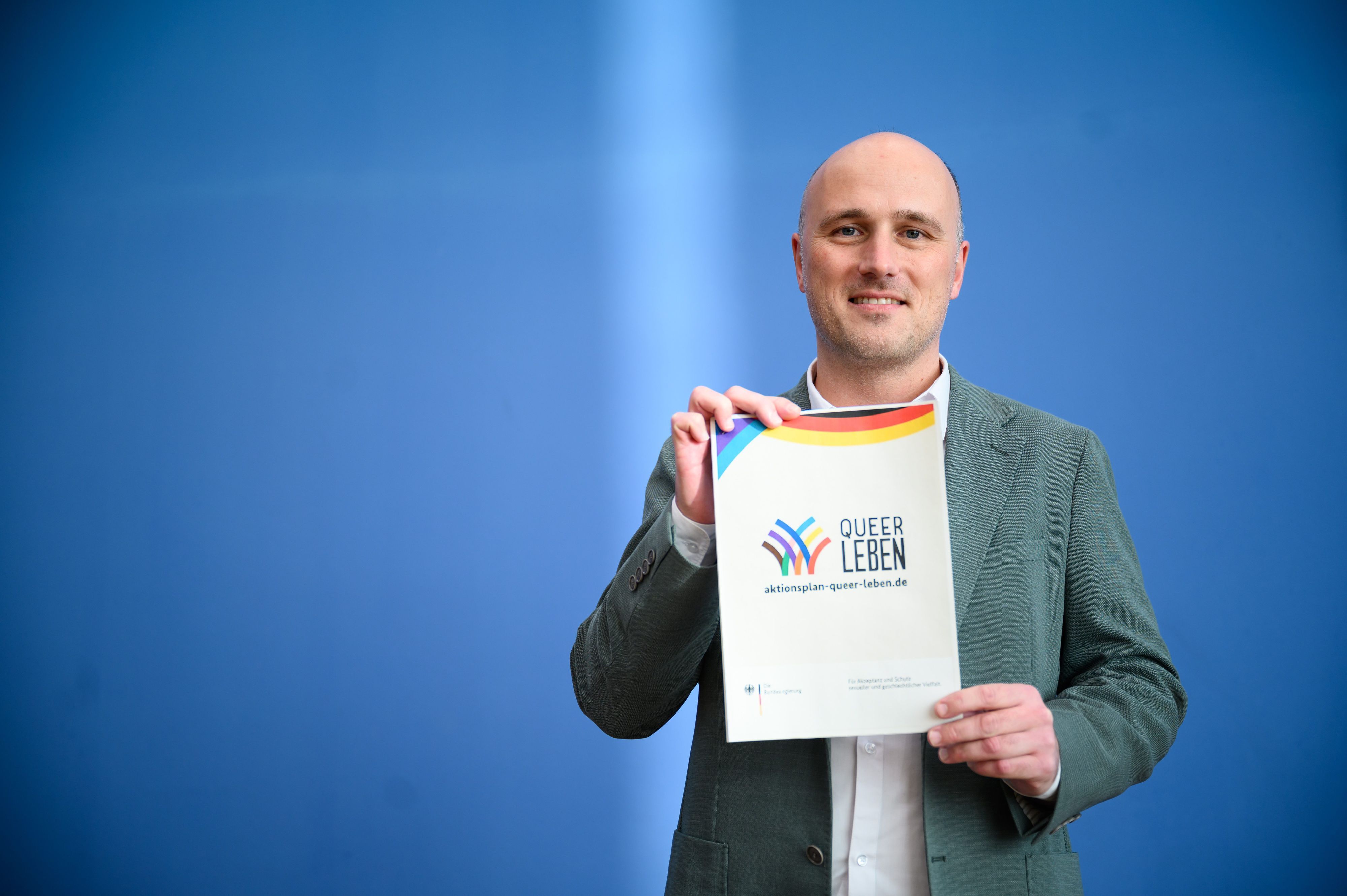 Sven Lehmann (Bündnis 90/Die Grünen), Parlamentarischer Staatssekretär im Bundesministerium für Familie, Senioren, Frauen und Jugend und Queer-Beauftragter der Bundesregierung, hält den ersten Aktionsplan der Bundesregierung «Queer leben» für Akzeptanz und Schutz sexueller und geschlechtlicher Vielfalt hoch