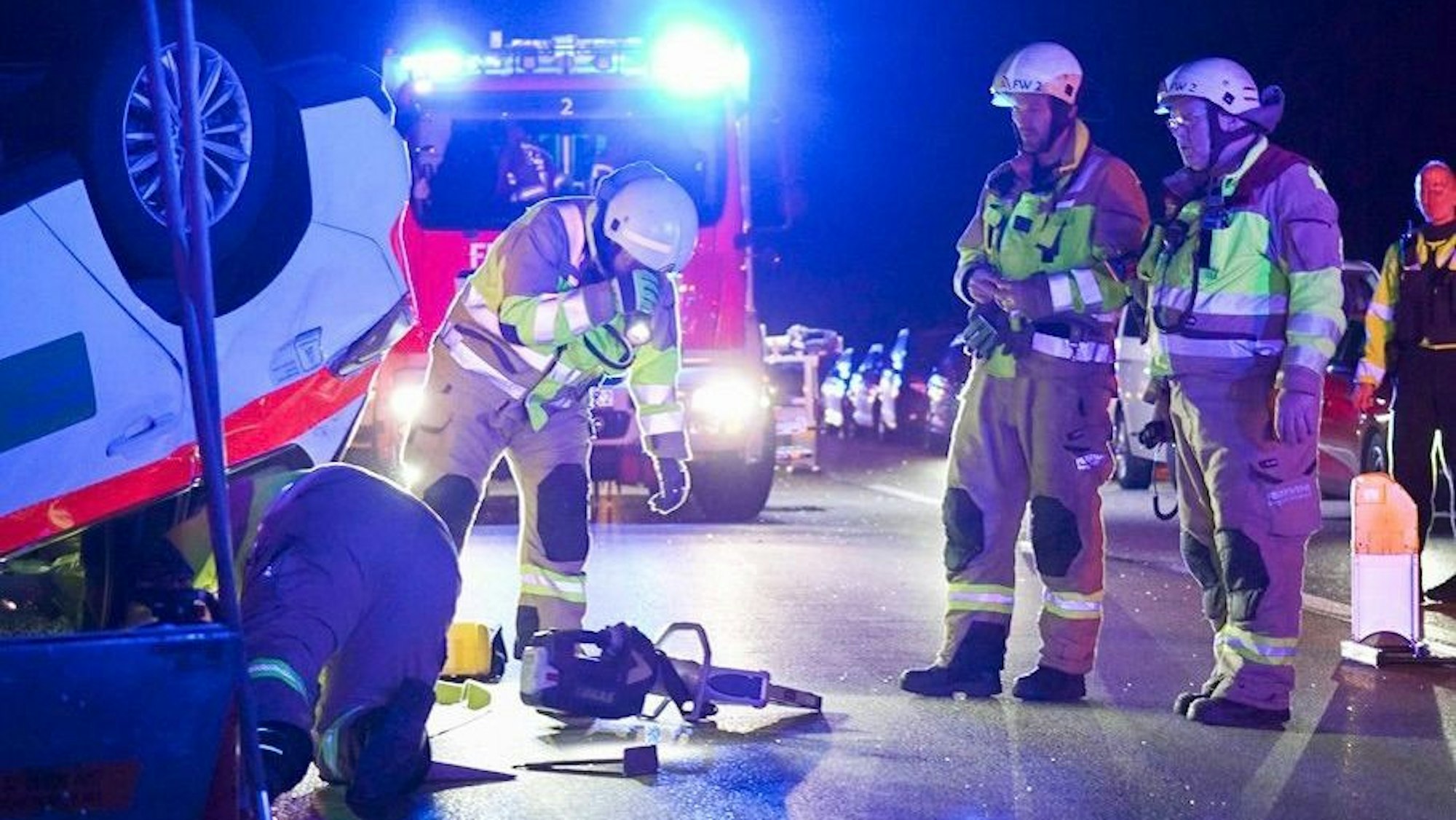 Die Einsatzkräfte der Feuerwehr auf der A4 an einem Unfallauto, das auf dem Dach liegt.