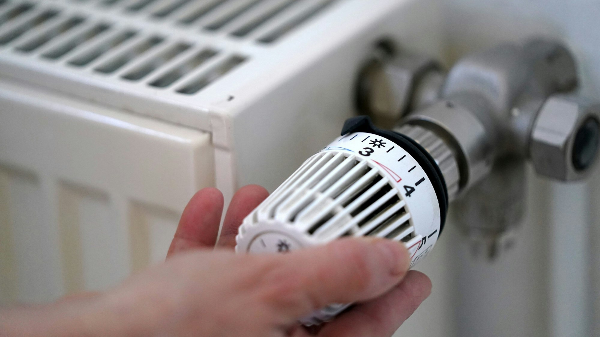Eine Frau dreht an einem Heizungsthermostat