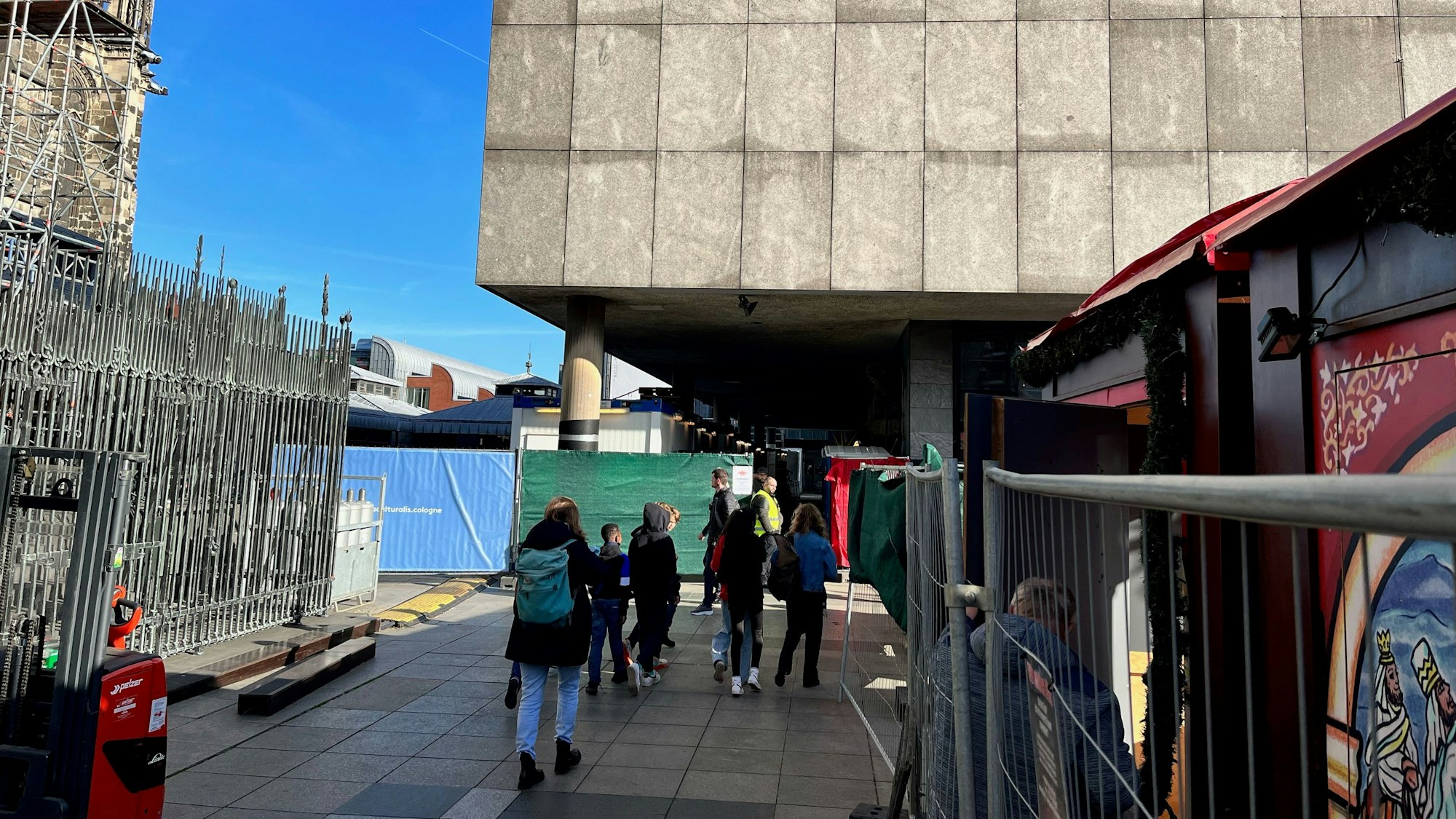 Passanten laufen an den Weihnachtsmarktbuden auf den gesperrten Durchgang zwischen Römisch-Germanischem Museum und Dombauhütte zu.