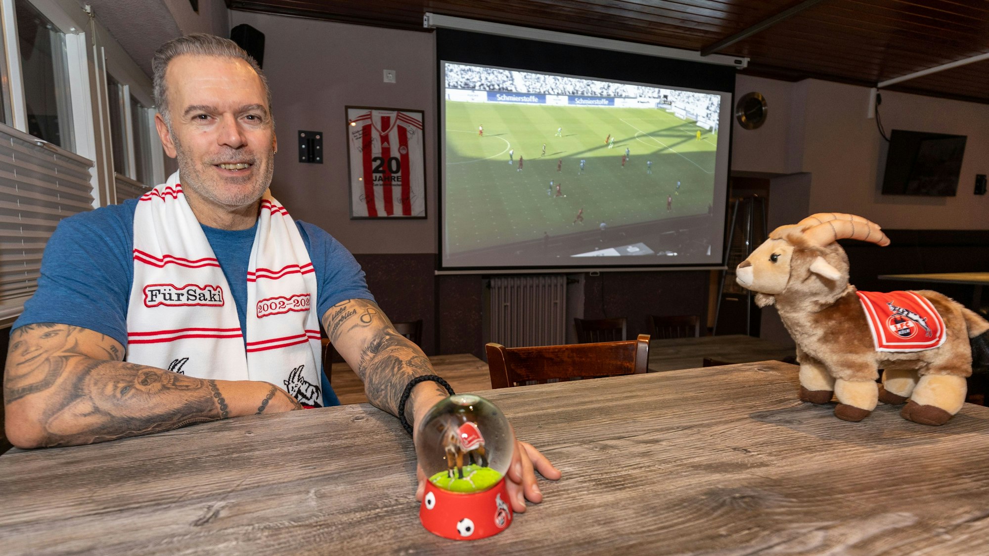 FC-Fan Athanasios Anagnostou zeigt in seiner Kneipe die WM-Spiele aus Katar auf einer großen Leinwand.