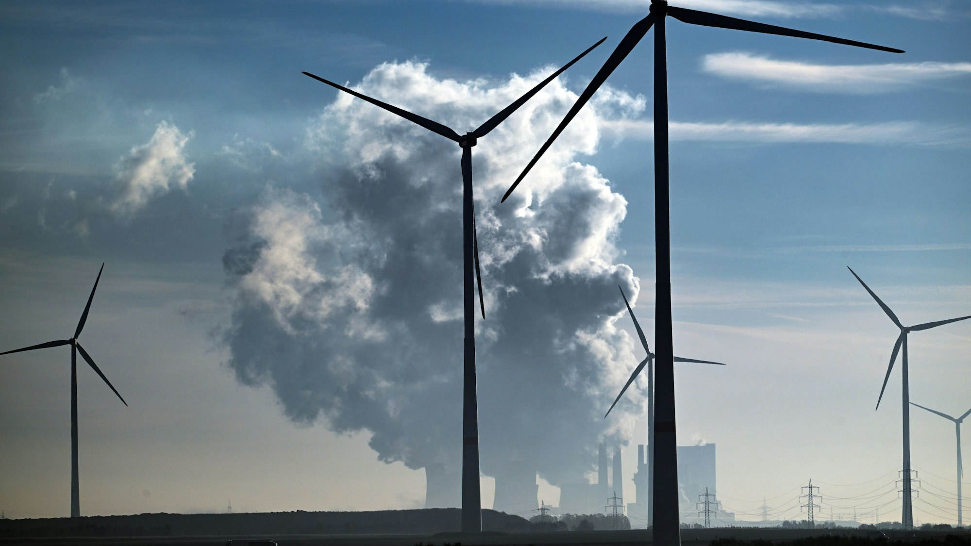 19.10.2022, Nordrhein-Westfalen, Jüchen: Windräder zur Stromerzeugung stehen am Rand des Braunkohletagebau Garzweiler. Im Hintergrund steht das Braunkohlekraftwerk Neurath. Der Kohleausstieg im Rheinischen Revier in Nordrhein-Westfalen soll um acht Jahre auf das Jahr 2030 vorgezogen werden. Angesichts der aktuellen Energiekrise sollen zugleich zwei Braunkohlekraftwerke länger als bisher geplant laufen. Foto: Federico Gambarini/dpa +++ dpa-Bildfunk +++