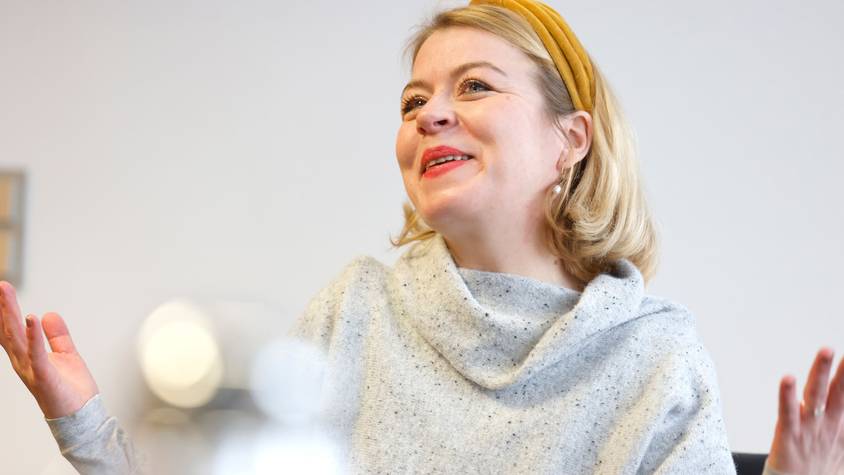 Die neue Intendantin des Hänneschen-Theaters lächelt und gestikuliert mit den Händen während des Rundschau-Interviews.