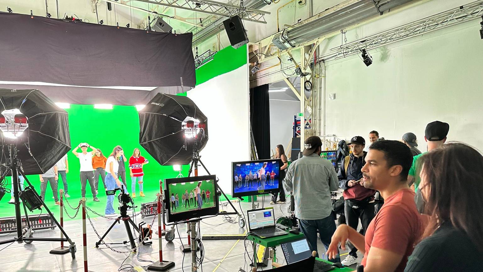 Ein Regisseur blickt auf einen Greenscreen mit mehreren Tänzern.