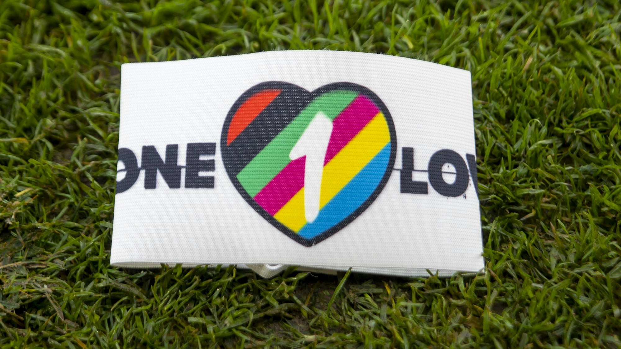 Die One Love-Armbinde liegt auf einem Rasenstück.