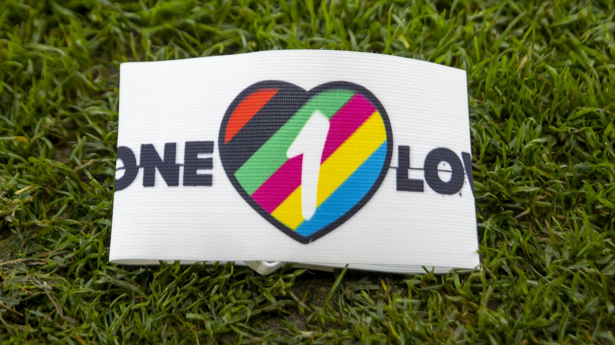 Die One Love-Armbinde liegt auf einem Rasenstück.