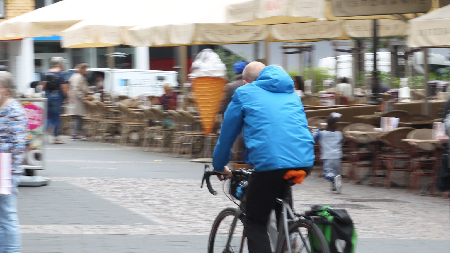 Ein Fahrradfahrer mit einer blauen Jacke radelt in Siegburg über den Markt.