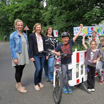 Schüler der Grundschüler Diesterwegstraße, Lehrer und Eltern präsentieren ihre selbsteingerichtete Straßensperrung vor der Schule.