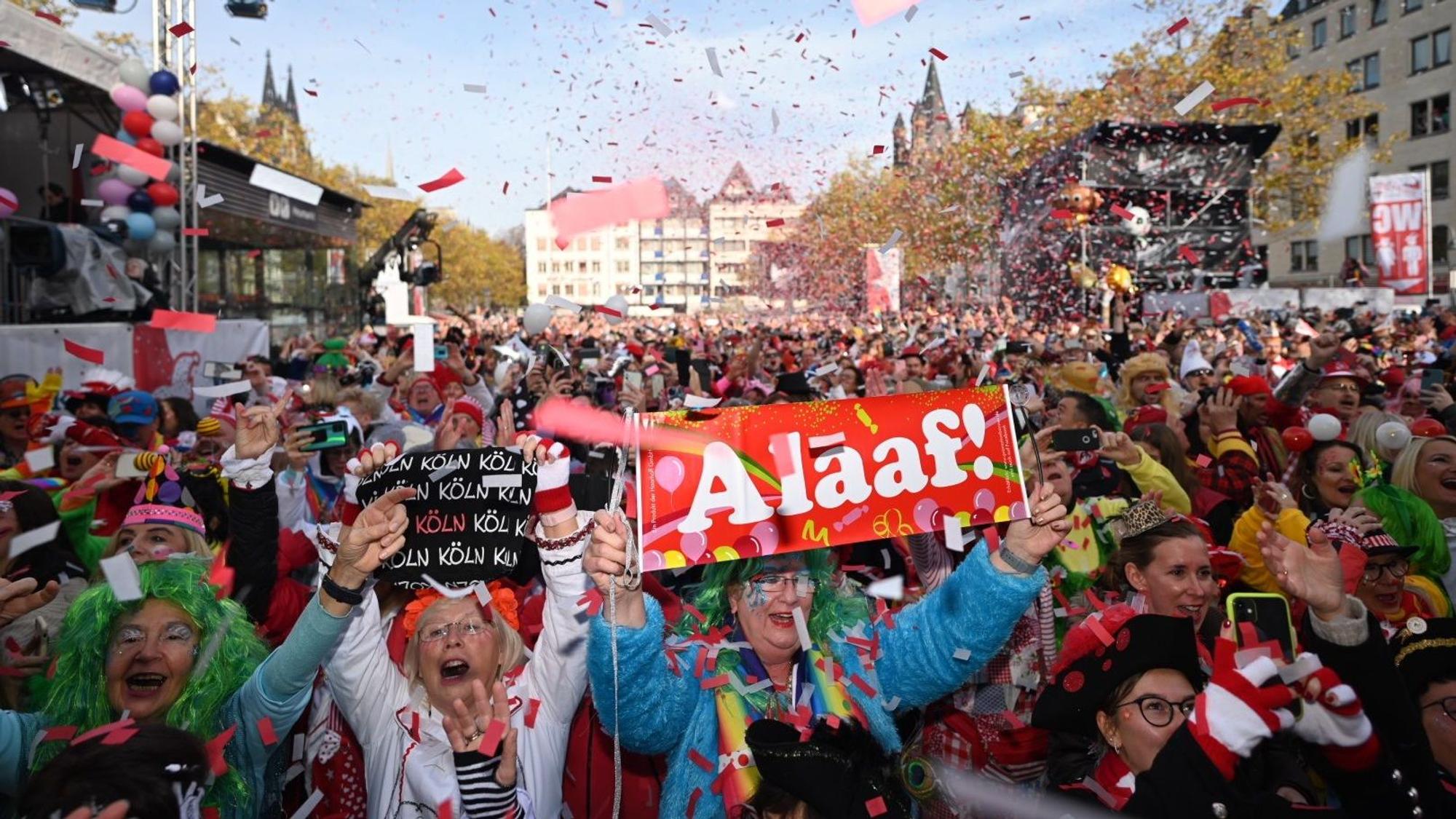 Das Bild zeigt den Heumarkt am Elften Elften. Dort wurde die Karnevalssession offiziell eröffnet. Menschen jubeln und durch die Luft fliegt Konfetti.
