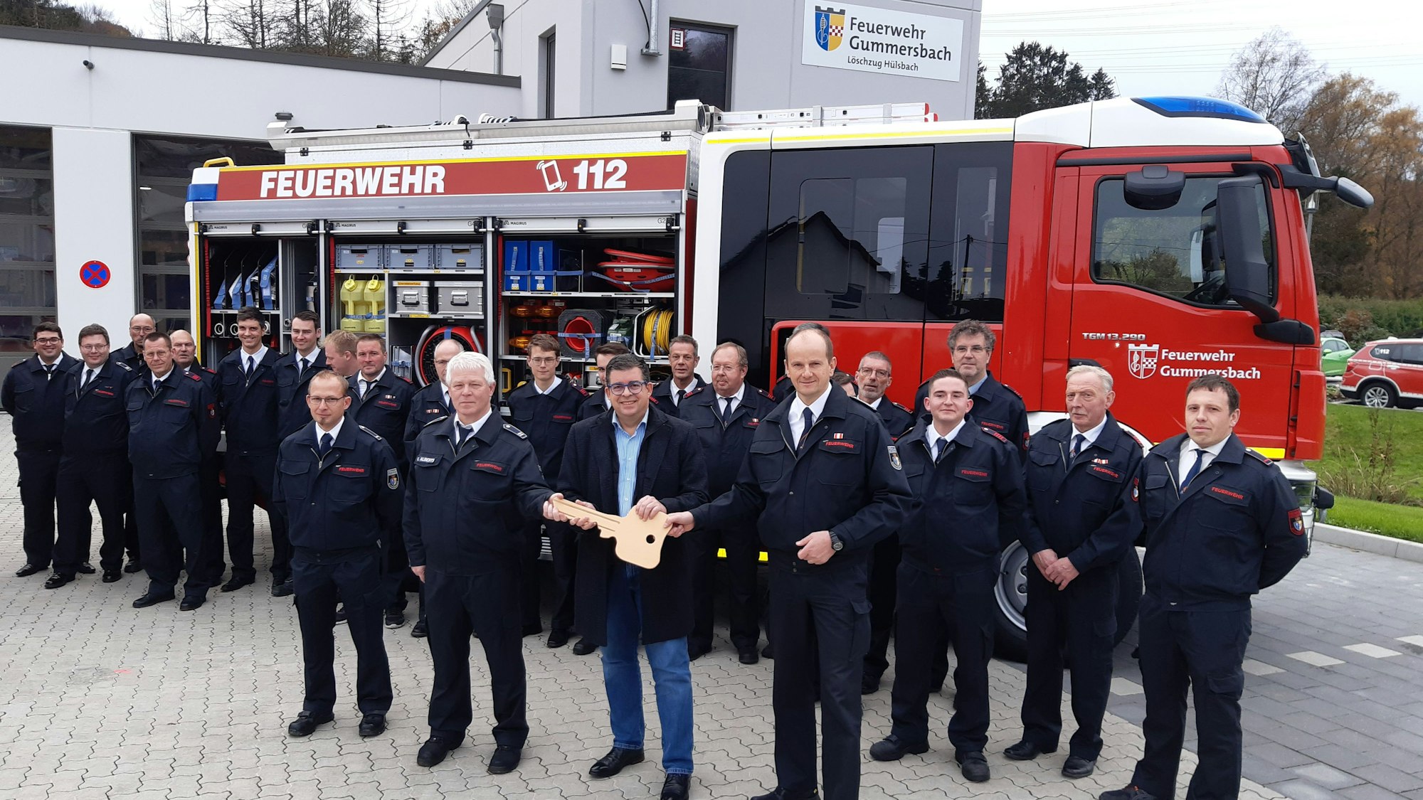 Bürgermeister Frank Helmenstein hält symbolisch für die Fahrzeugübergabe einen großen goldenen Schlüssel in der Hand. Diesen übergibt er an Feuerwehrchef Frank Raupach und die stellvertretenden Einheitsführer Stephan Schulte und Kai Alberts.