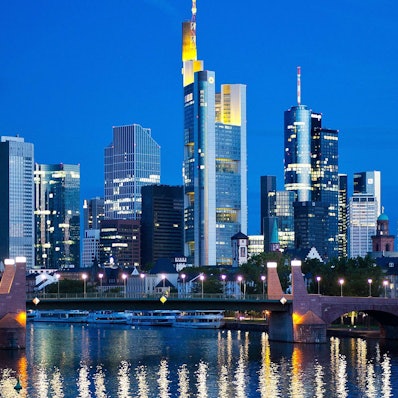 ARCHIV - Im ersten Licht des Tages spiegeln sich am 26.08.2015 die Lichter der Skyline von Frankfurt am Main (Hessen) im Wasser des Mains. Foto: Christoph Schmidt/dpa