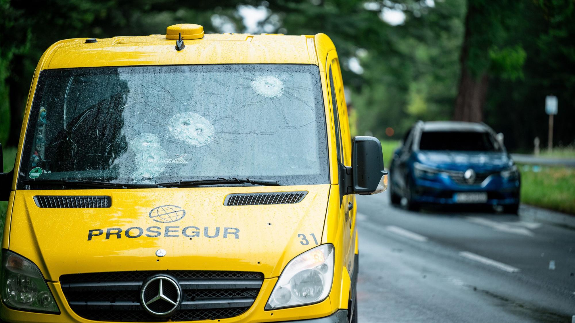 Ein durch Schüsse beschädigter Geldtransporter steht am Straßenrand.