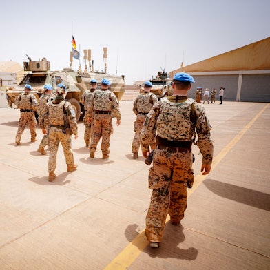 Soldaten der Bundeswehr marschieren im Camp Castor in Mali. Im Hintergrund sind Militärfahrzeuge zu sehen.
