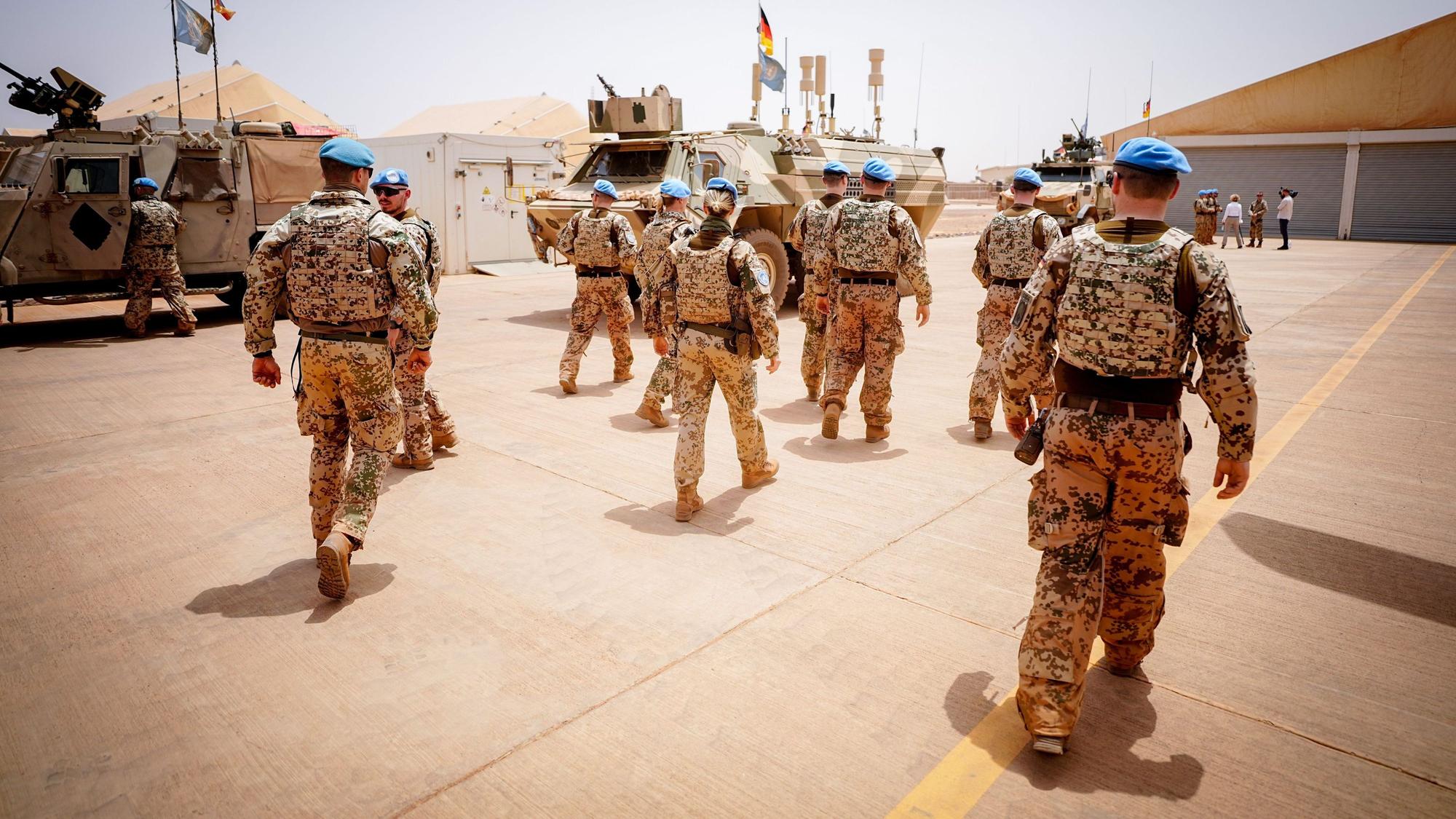 Soldaten der Bundeswehr marschieren im Camp Castor in Mali. Im Hintergrund sind Militärfahrzeuge zu sehen.