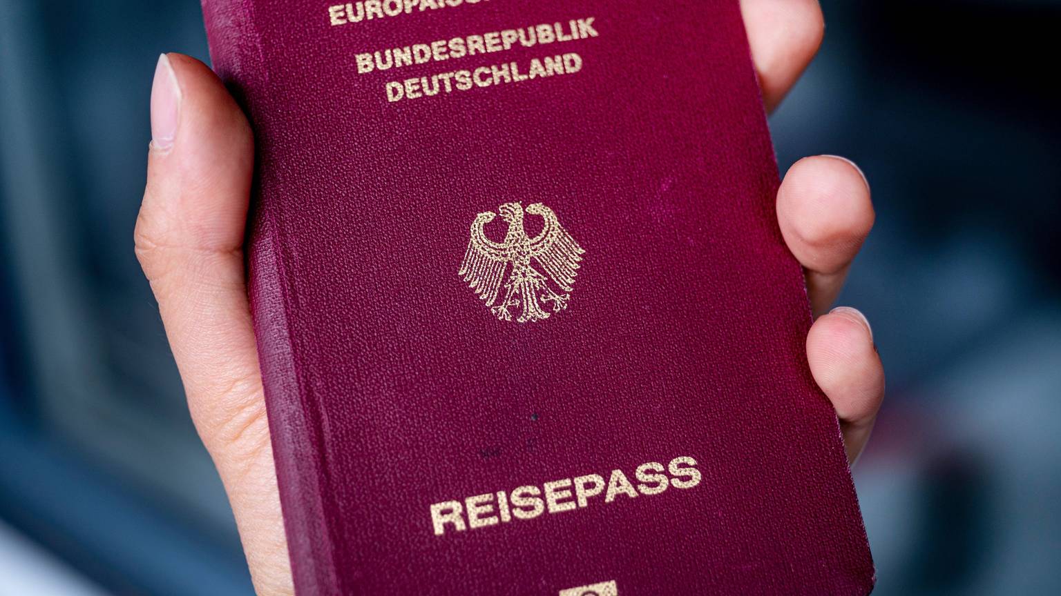 Eine Person hält in einer Hand einen deutschen Reisepass.