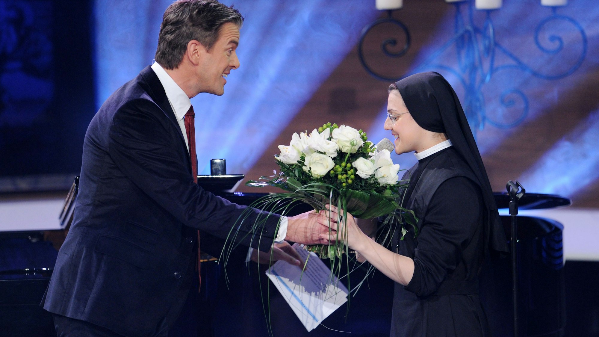 Die Nonne Cristina Scuccia und der Moderator Markus Lanz, aufgenommen am 02.12.2014 in München (Bayern) bei der Aufzeichnung der Sendung "Menschen 2014". Er überreicht ihr weiße Rosen.