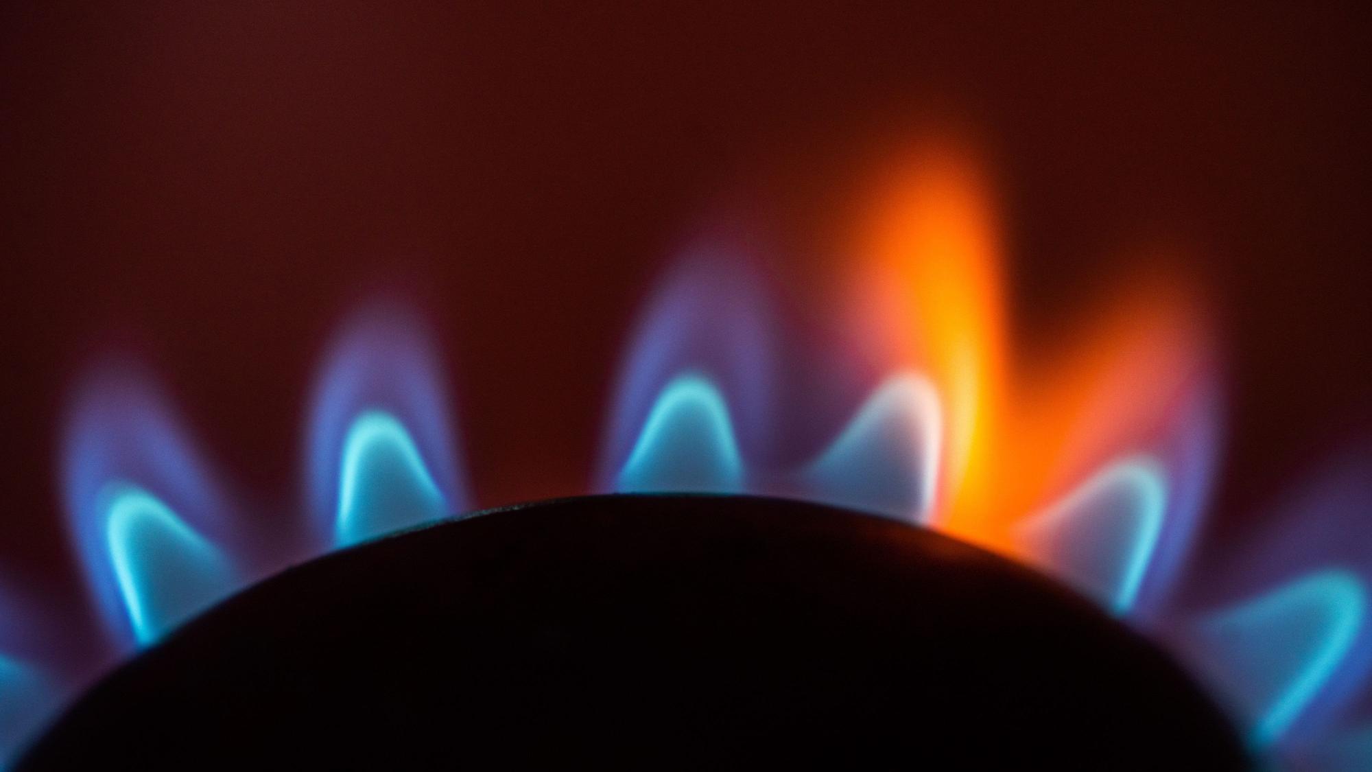 Die Flamme eines Gasherdes brennt in einer Küche.