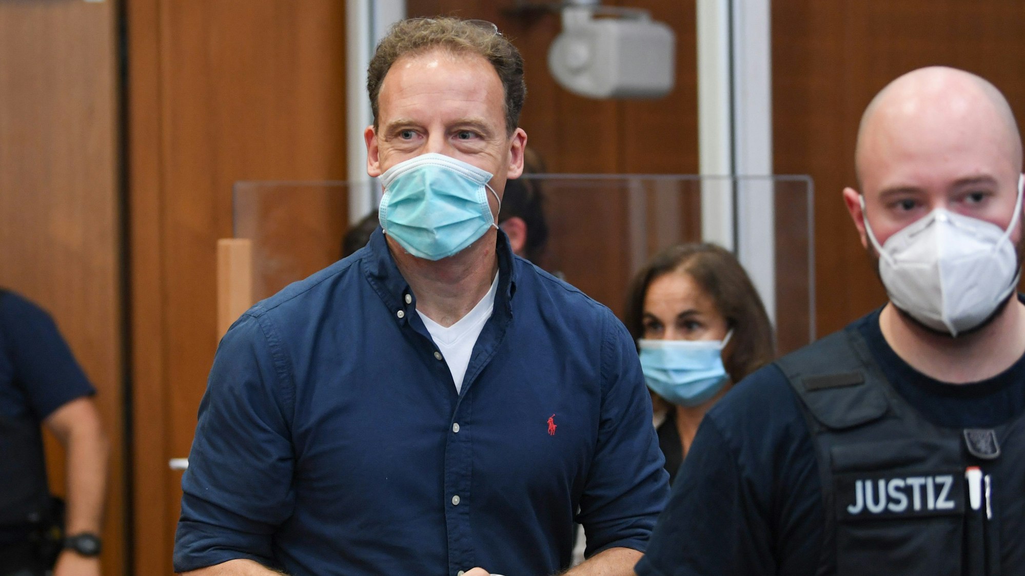 Der Unternehmer Alexander Falk kommt in Begleitung von Justizbeamten zur Urteilsverkündung in den Gerichtssaal des Landgerichts in Frankfurt am Main.