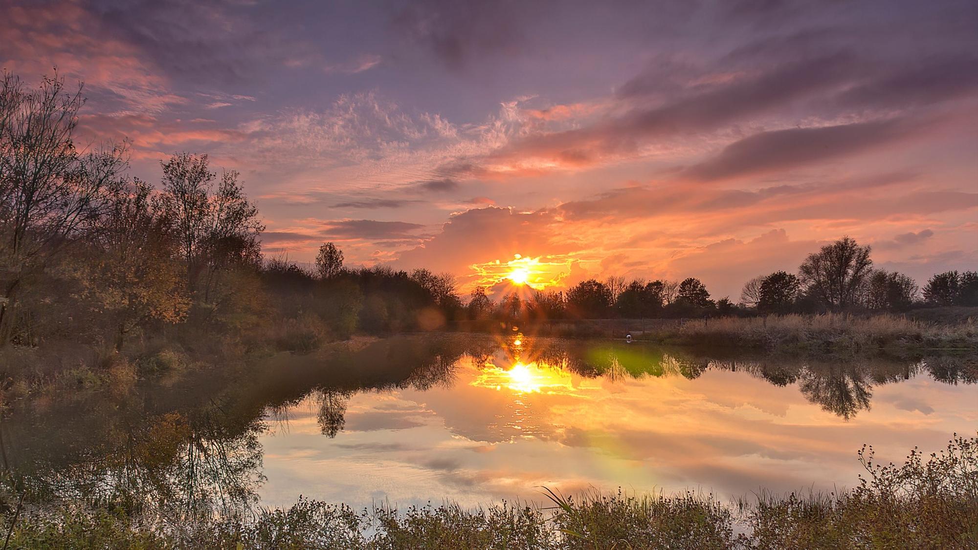 Über dem Teich geht die Sonne unter.