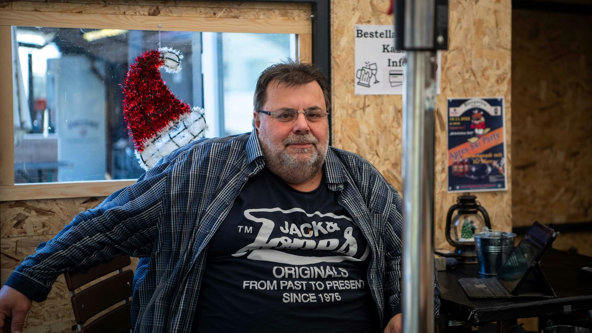 Wirt Helmut Wagner posiert hinter einem Heizpilz und vor einer Weihnachtsmütze.