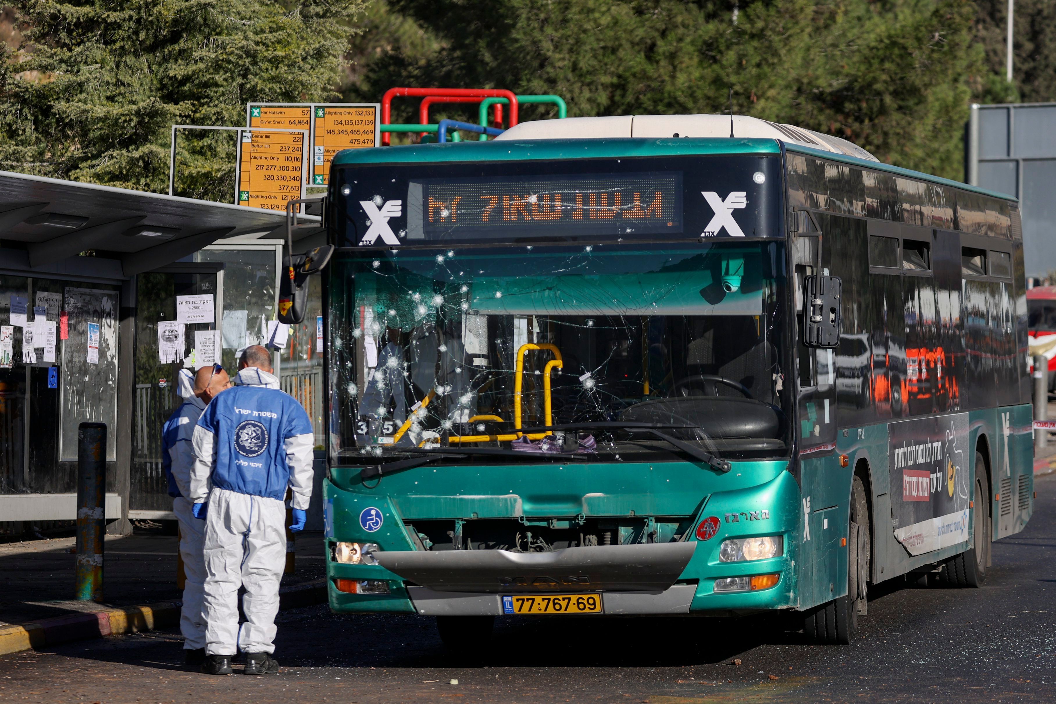 Israelische Polizisten der Spurensicherung ermitteln am Ort einer Explosion an einer Bushaltestelle. Der Bus, der davor steht, und die Haltestelle selbst sind stark beschädigt.